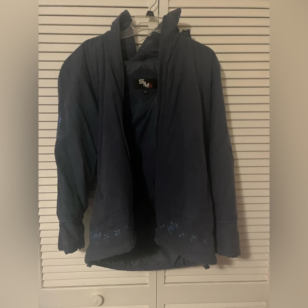 SMZ dark blue warm winter coat. Features embroidered detailed along the bottom.